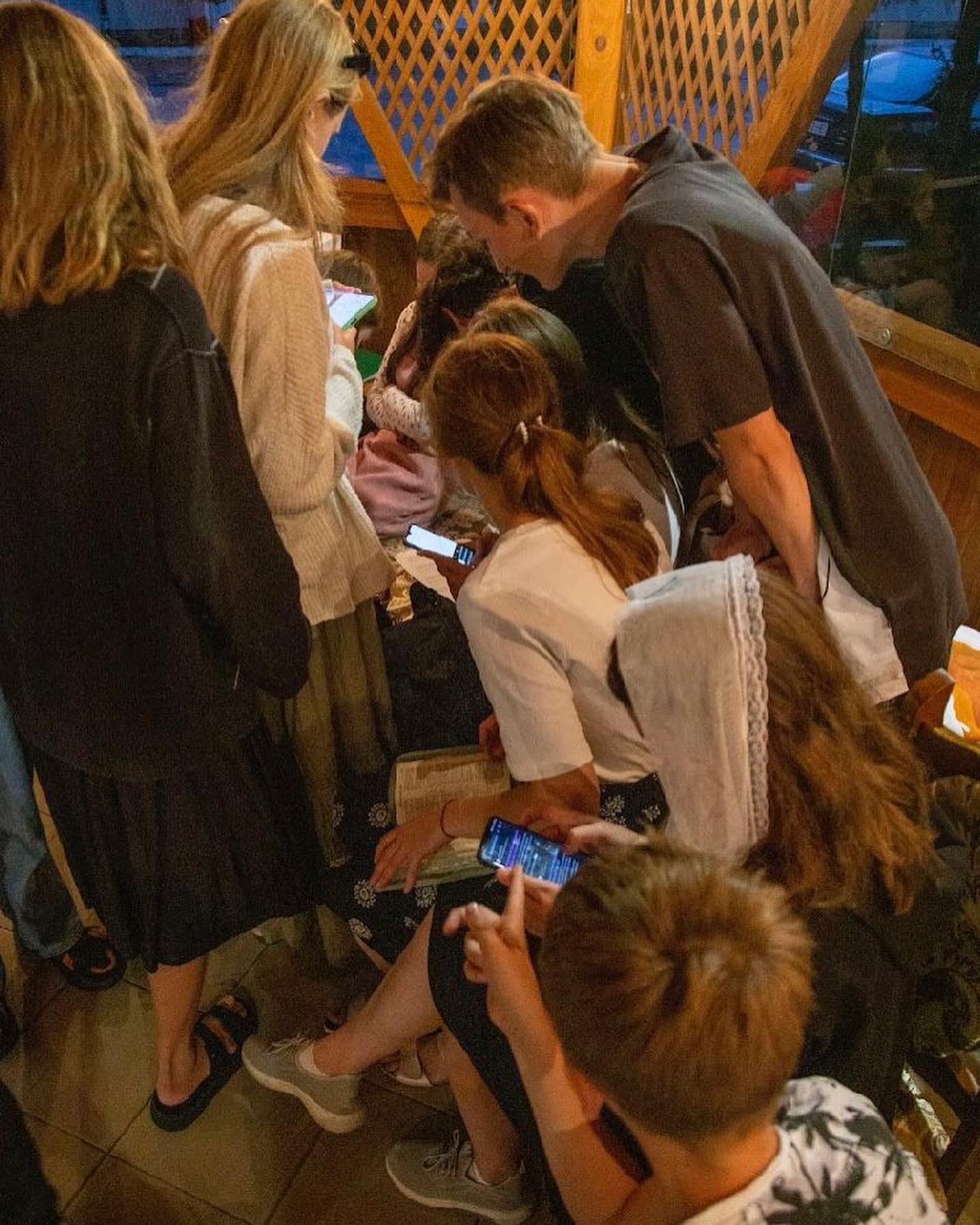A group of people looking at their phones in a restaurant.