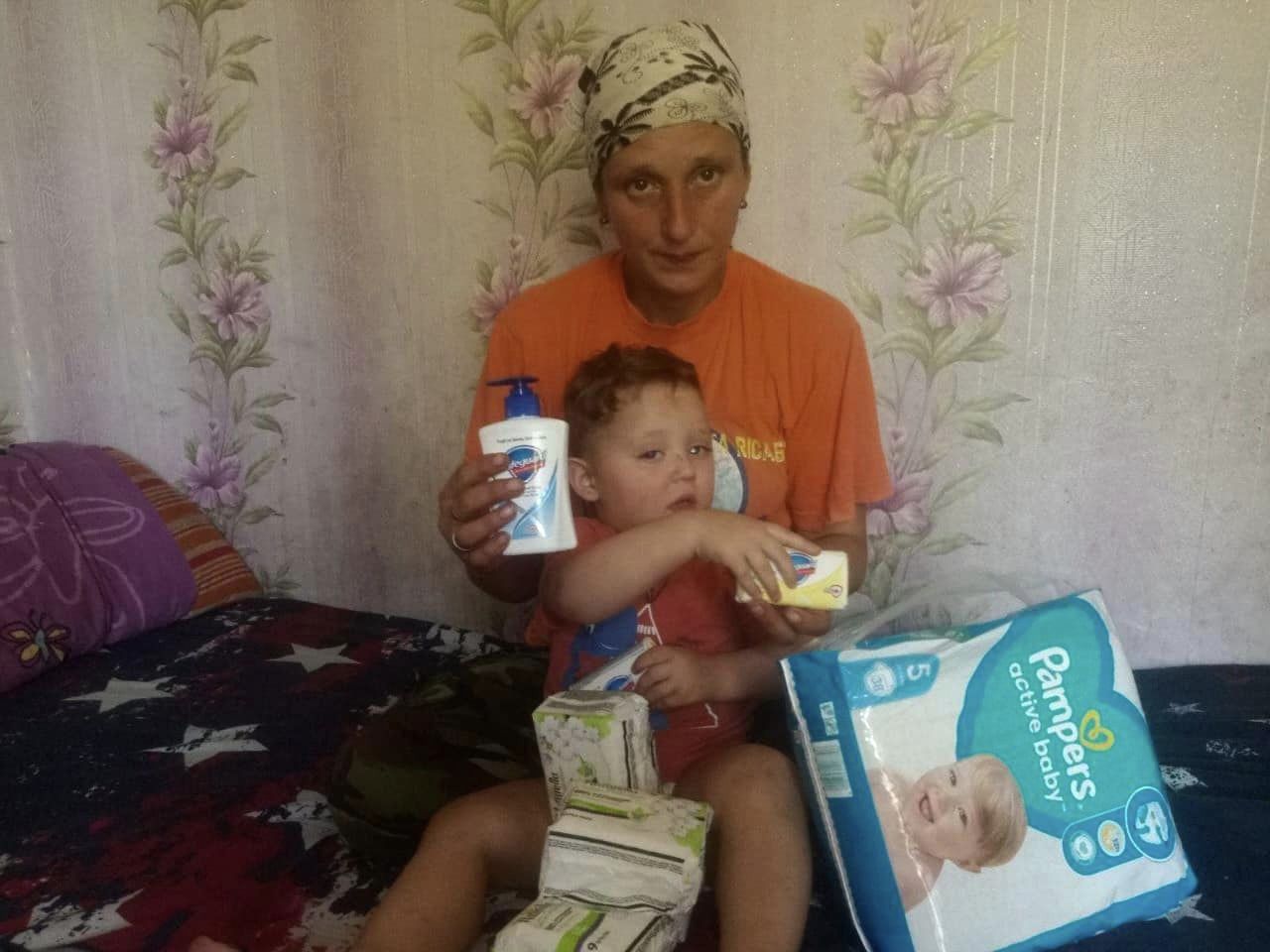 A woman and a child sitting on a bed with diapers.