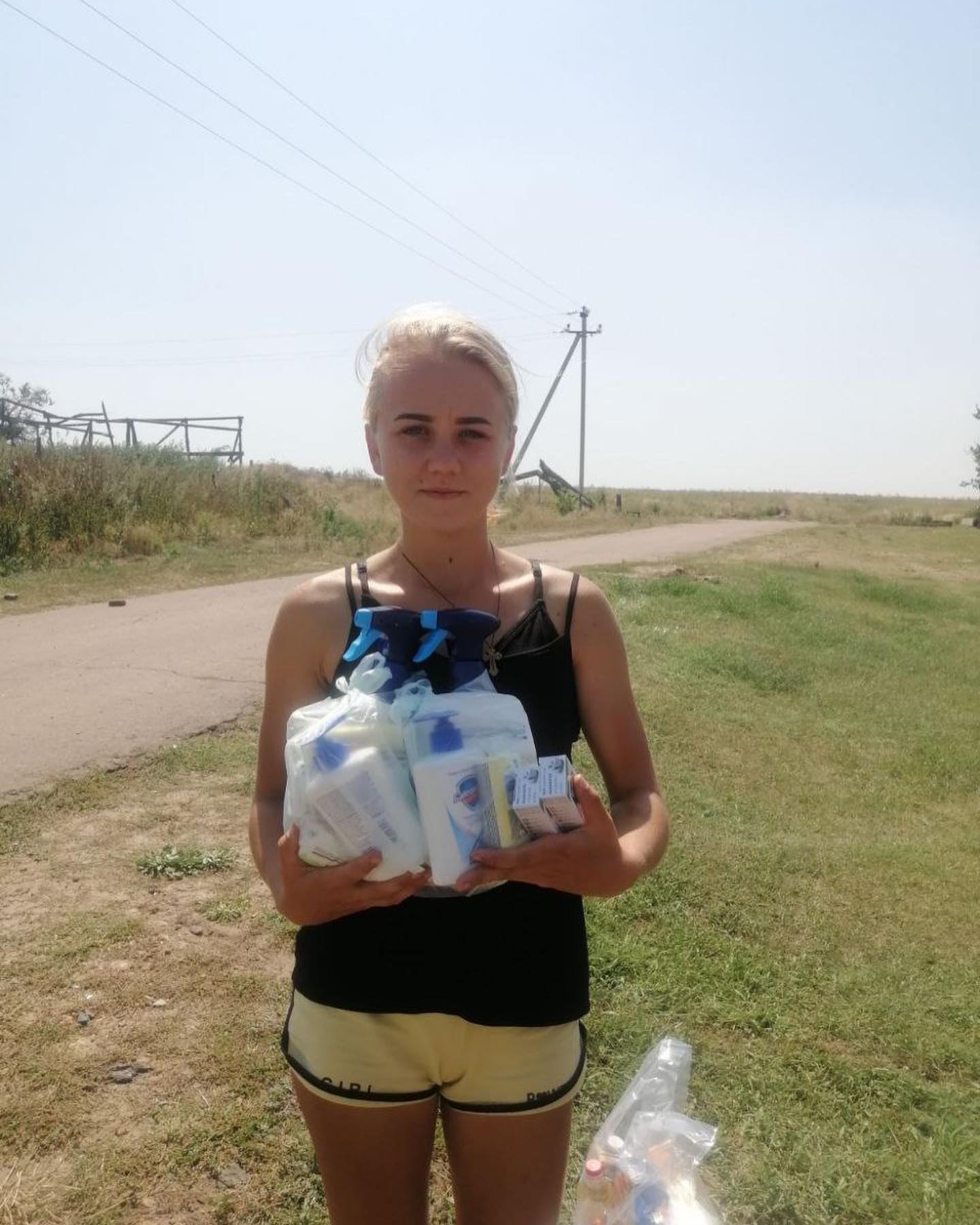 A young woman standing next to a road with bottles of water.