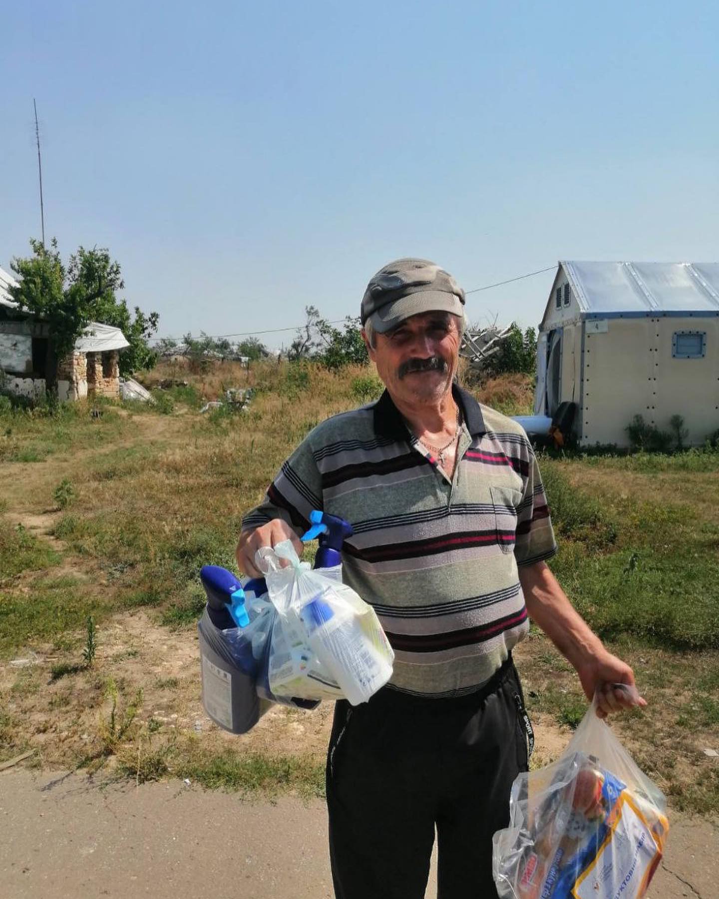 A man holding a bag of groceries in front of a house.
