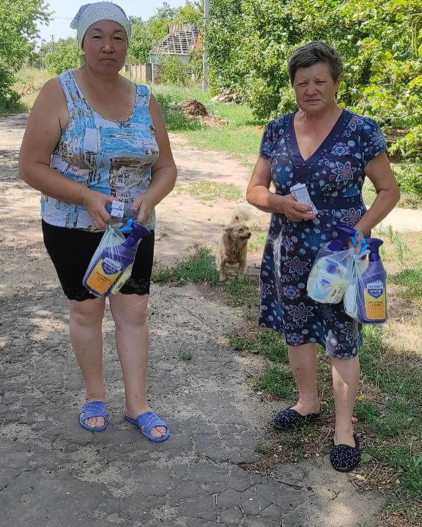 Two women standing next to each other holding bags.