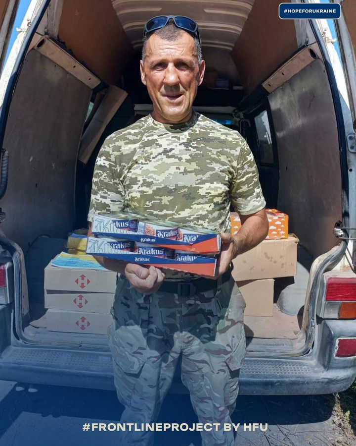 A man in camouflage holding a box of food.