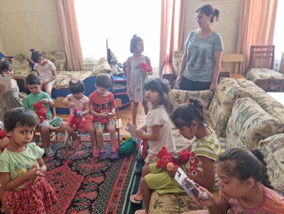 A group of children are sitting on a rug in a living room.