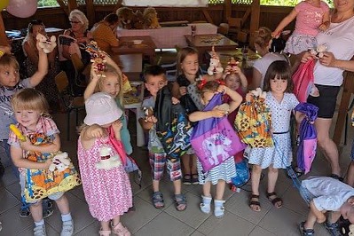 A group of children are holding bags in front of a table.