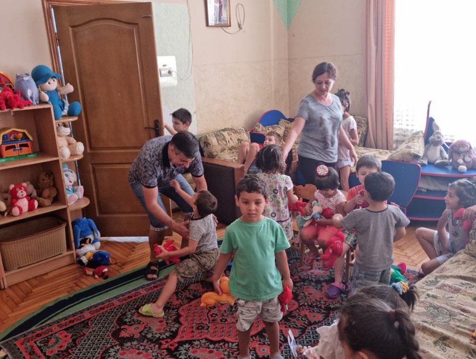 A group of children playing with stuffed animals in a living room.