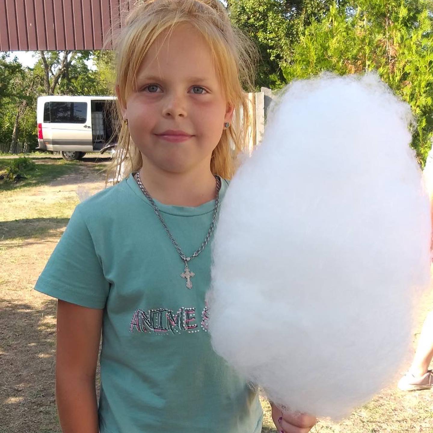 A young girl holding up a large cotton candy.