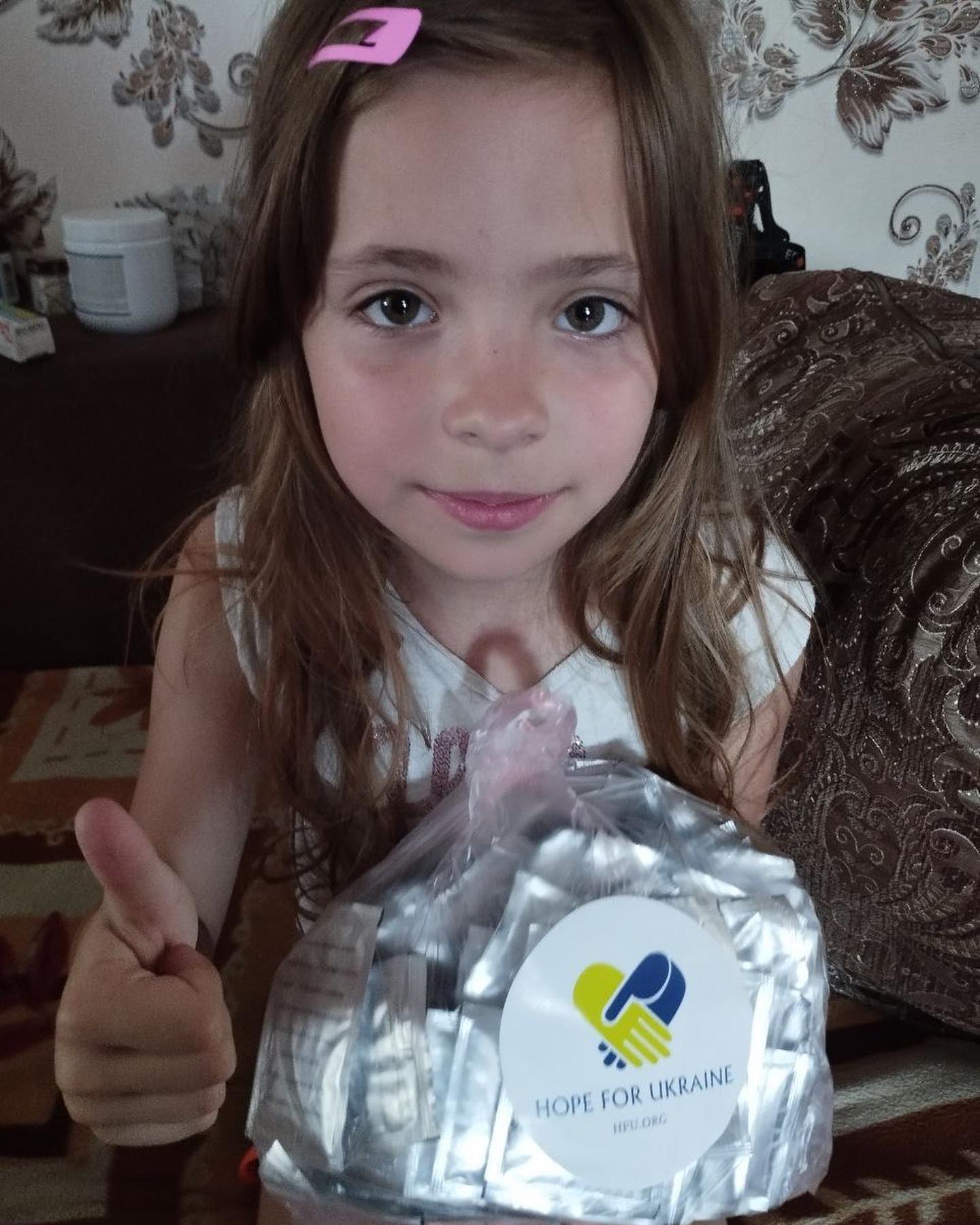 A little girl is holding a bag of pills.