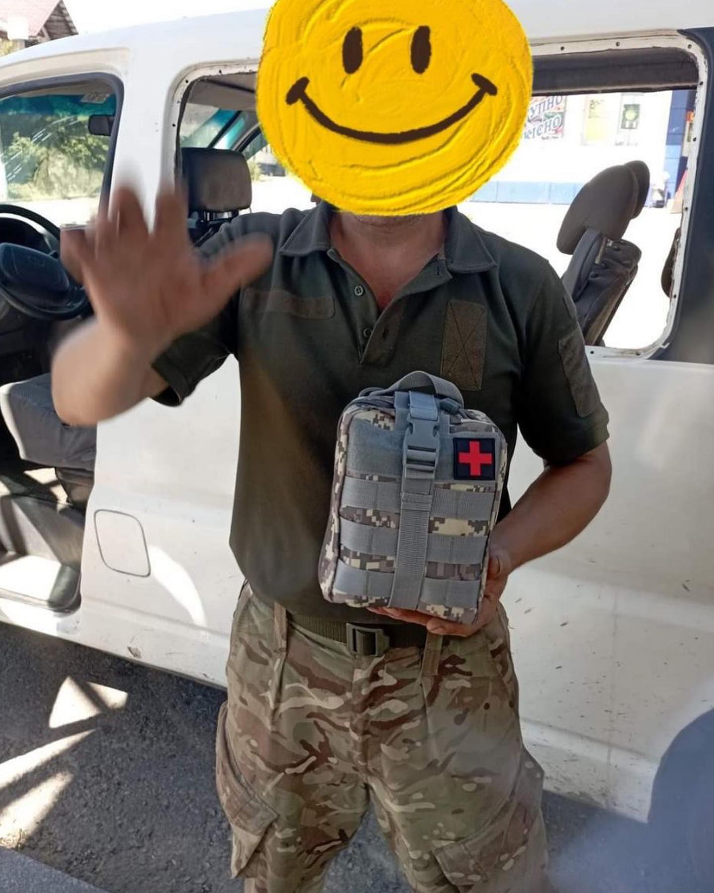 A soldier with a smiley face in front of a van.