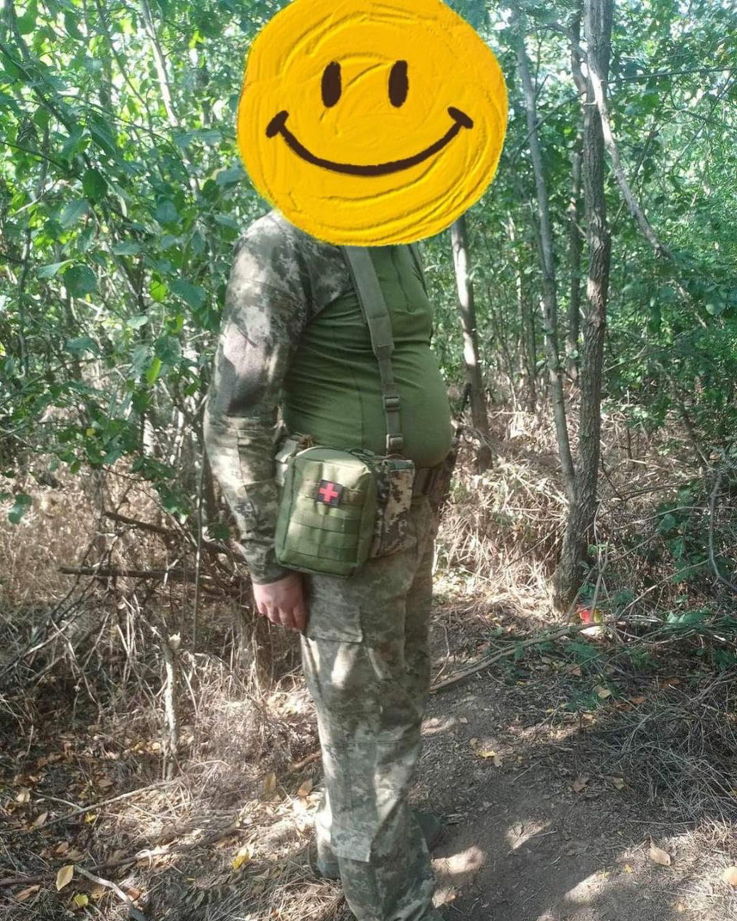 A man with a smiley face in the woods.