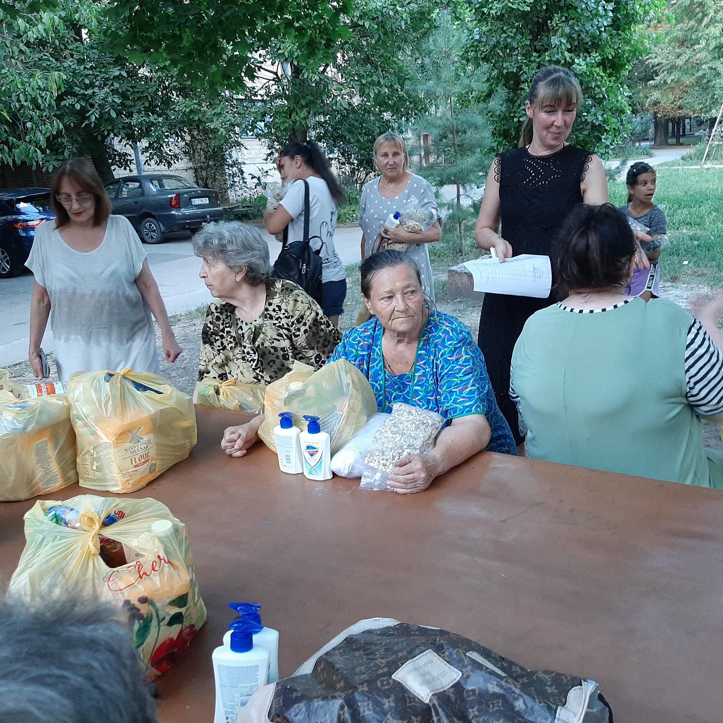 A group of people sitting around a table with bags of food.