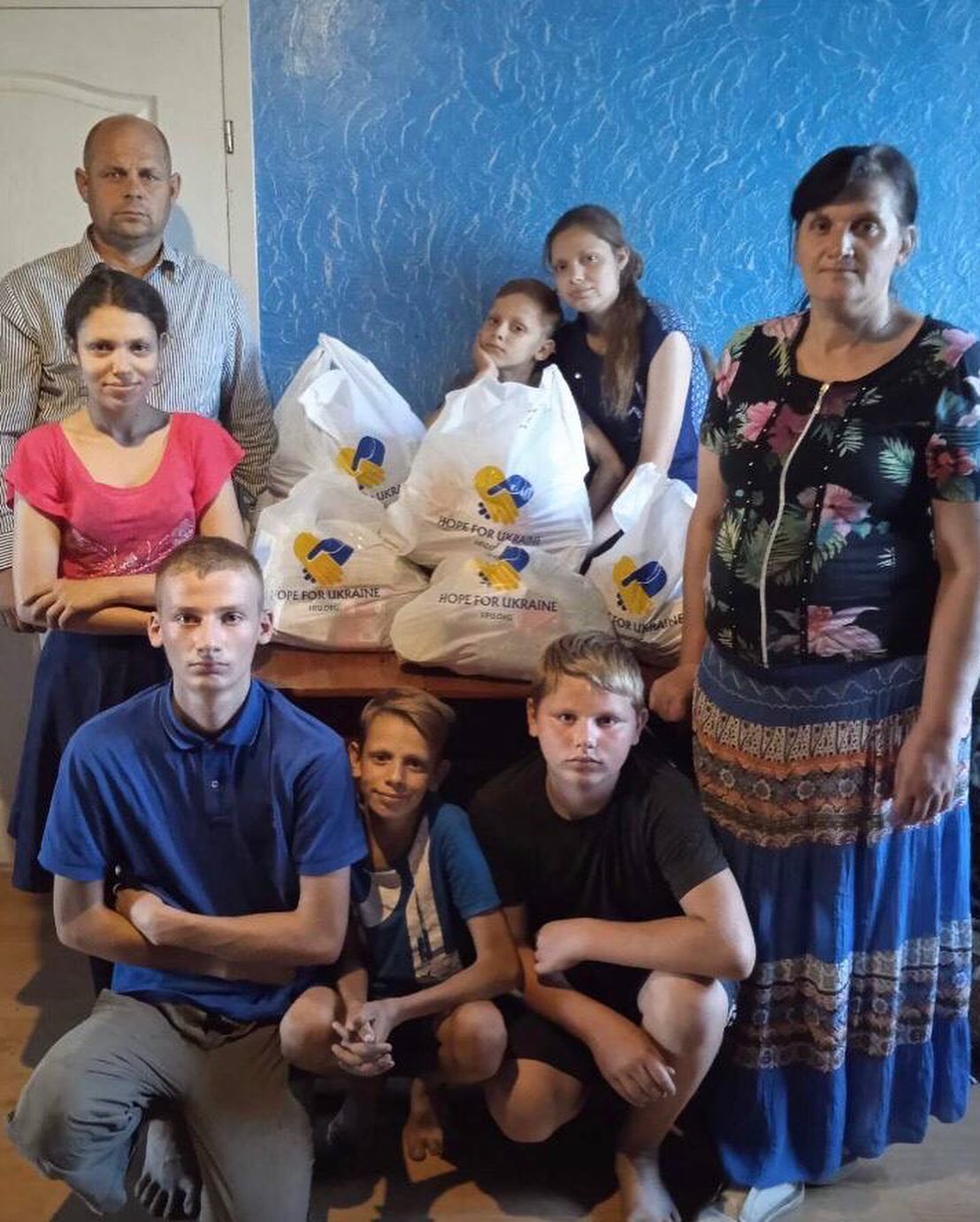 A group of people posing for a photo with bags of food.