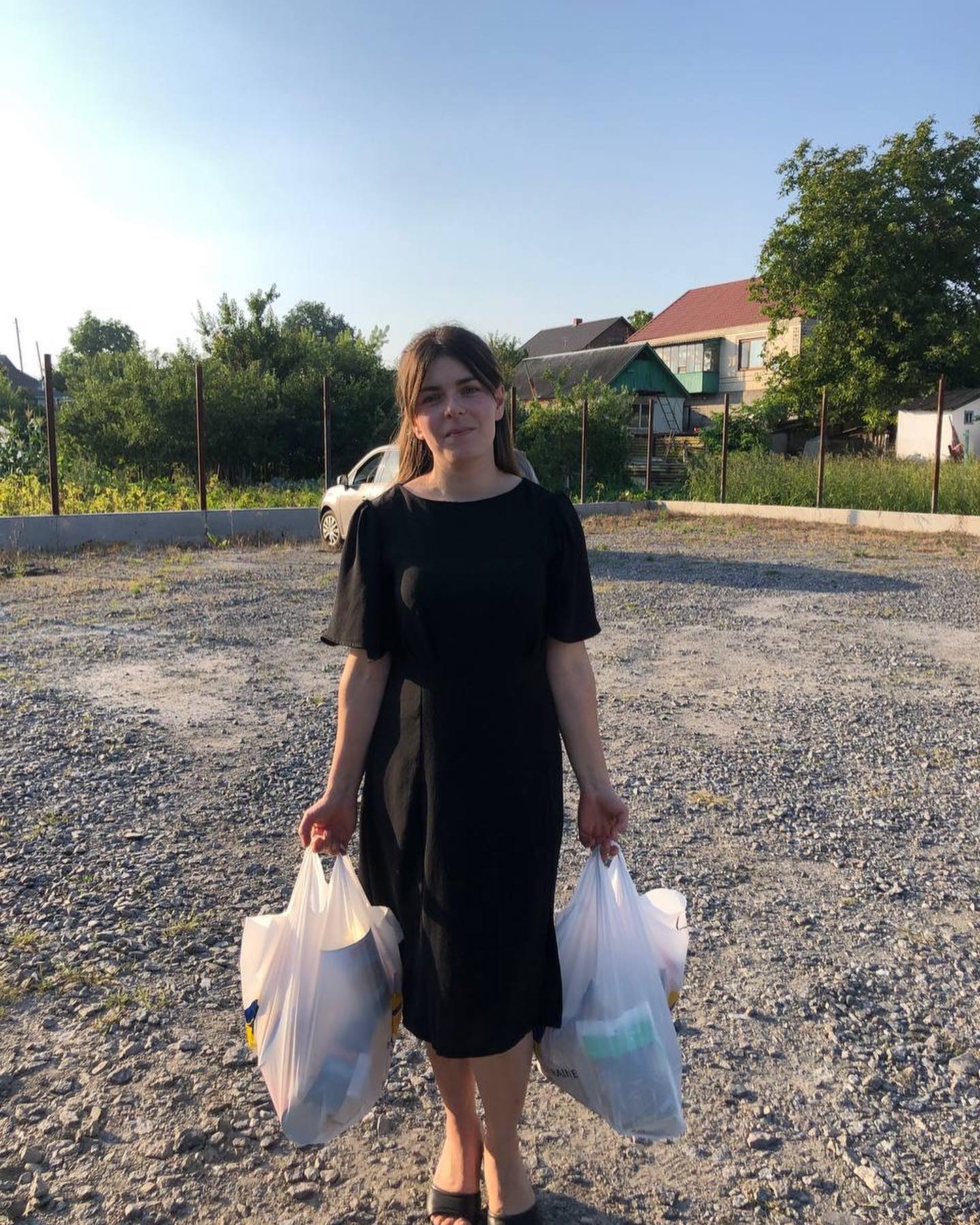 A woman in a black dress holding shopping bags.