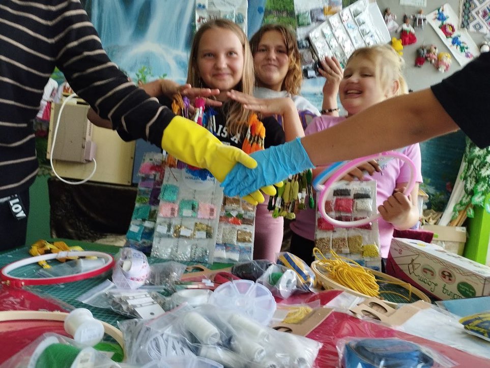 A group of young girls are holding hands with a table full of craft supplies.