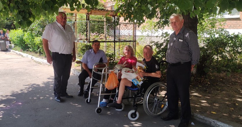 A group of people in wheelchairs posing under a tree.