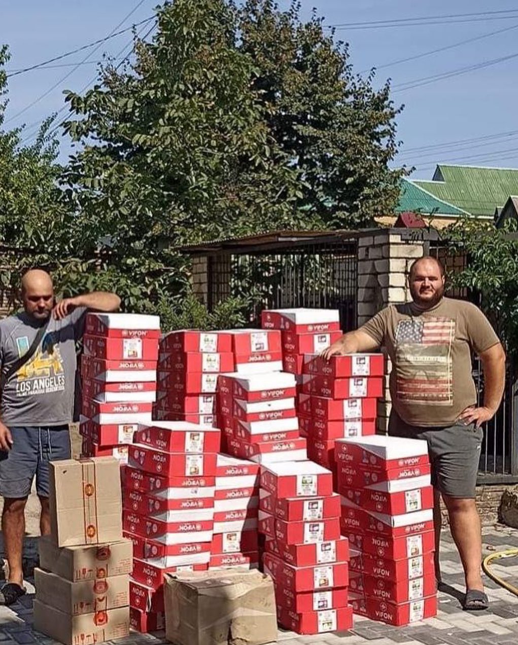Two men standing next to a pile of boxes.