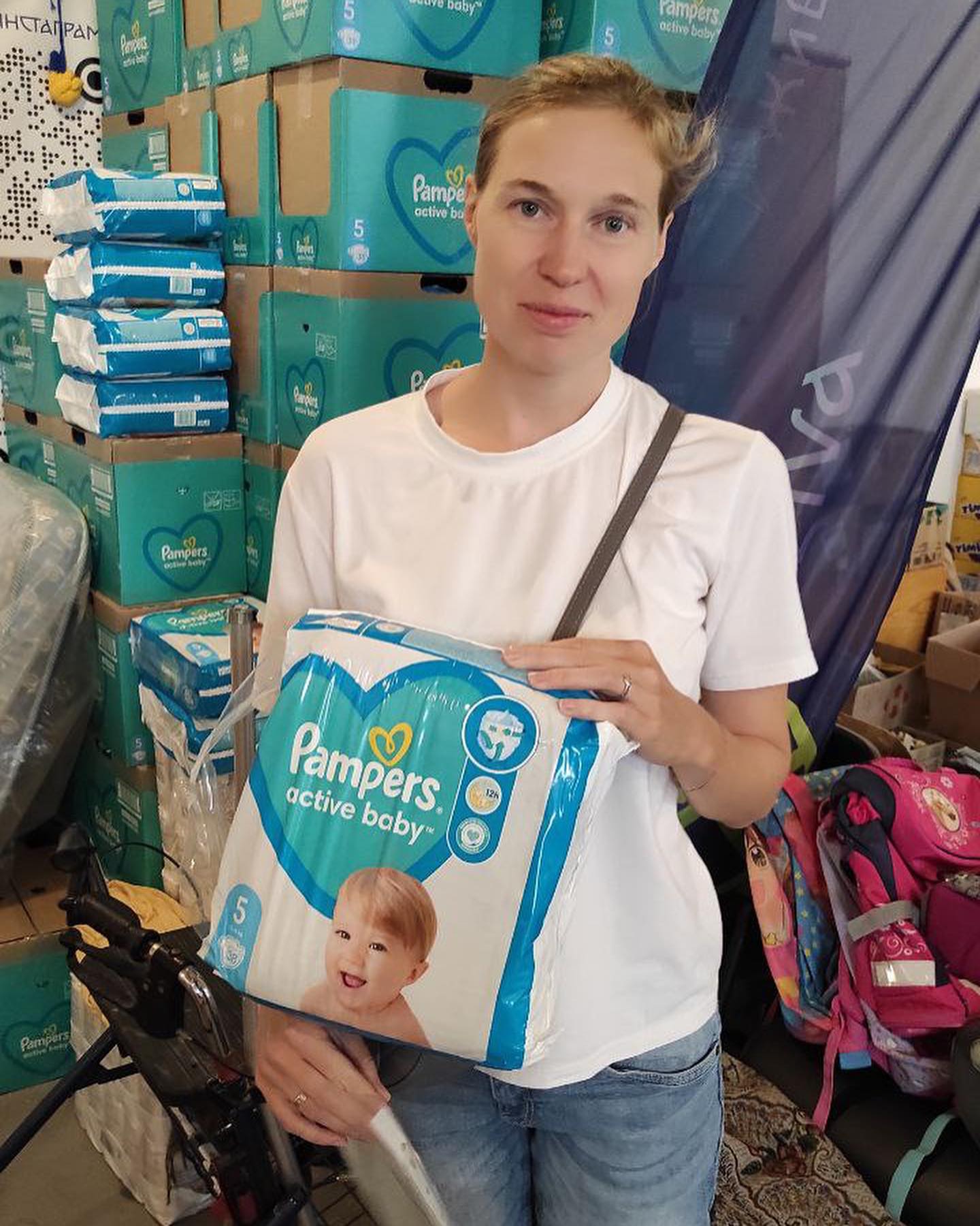 A woman holding a package of pampers diapers.