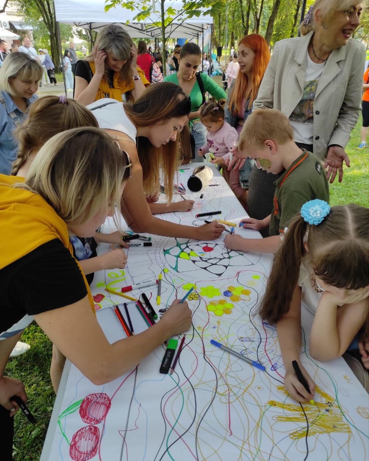 A group of children drawing on a table in a park.