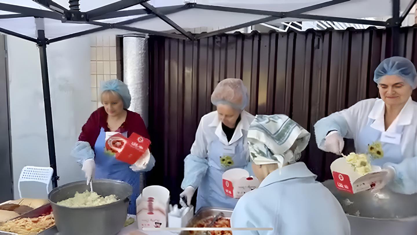 A group of women are preparing food under a tent.