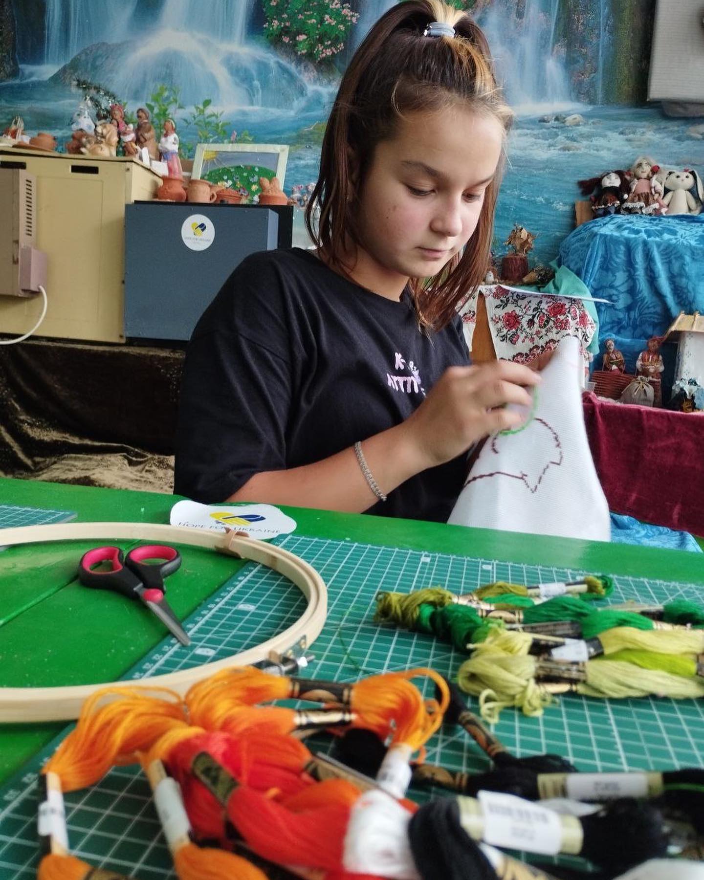 A girl is working on a hoop with colorful threads.