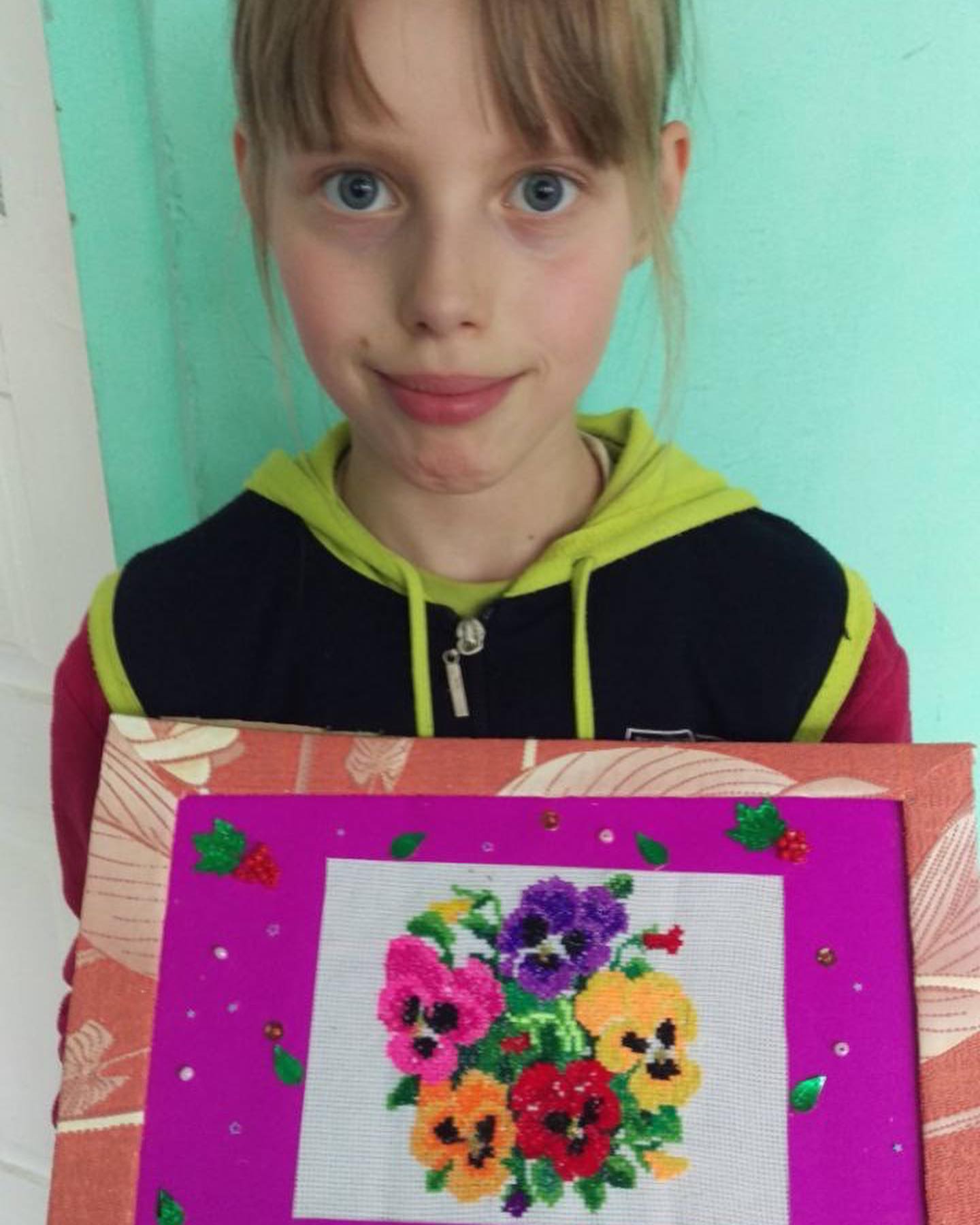 A girl holding up a picture of pansies.