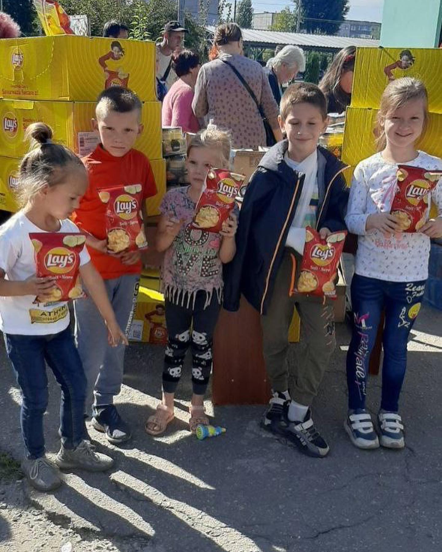 A group of children standing in front of a box of chips.