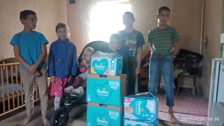 A group of children standing in front of boxes of diapers.