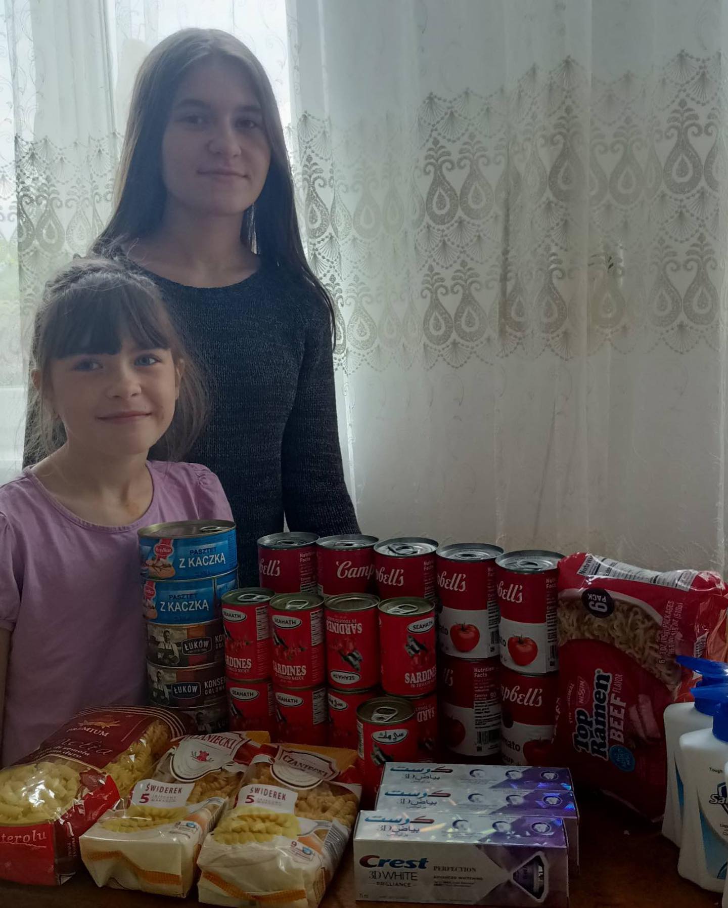 Two young girls standing next to a table full of food.