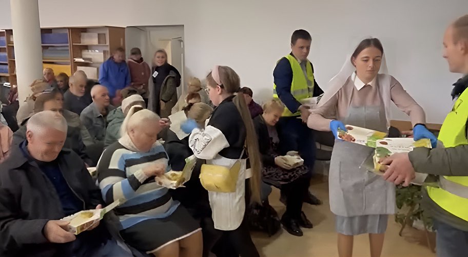 A group of people are serving food to people in a church.