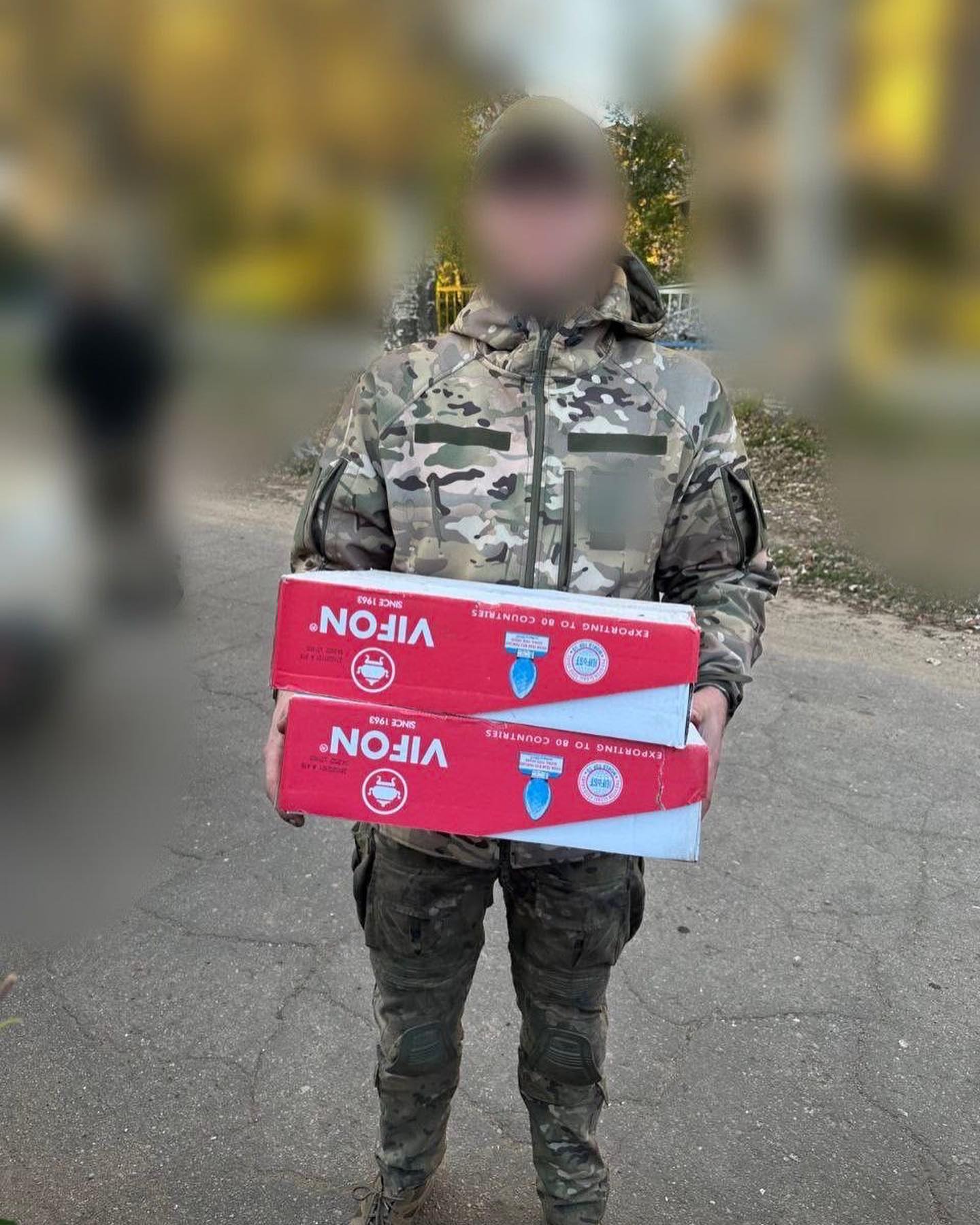 A man in a camouflage uniform holding a box.