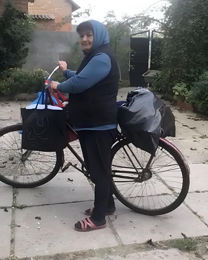 A woman standing next to a bicycle with bags on it.