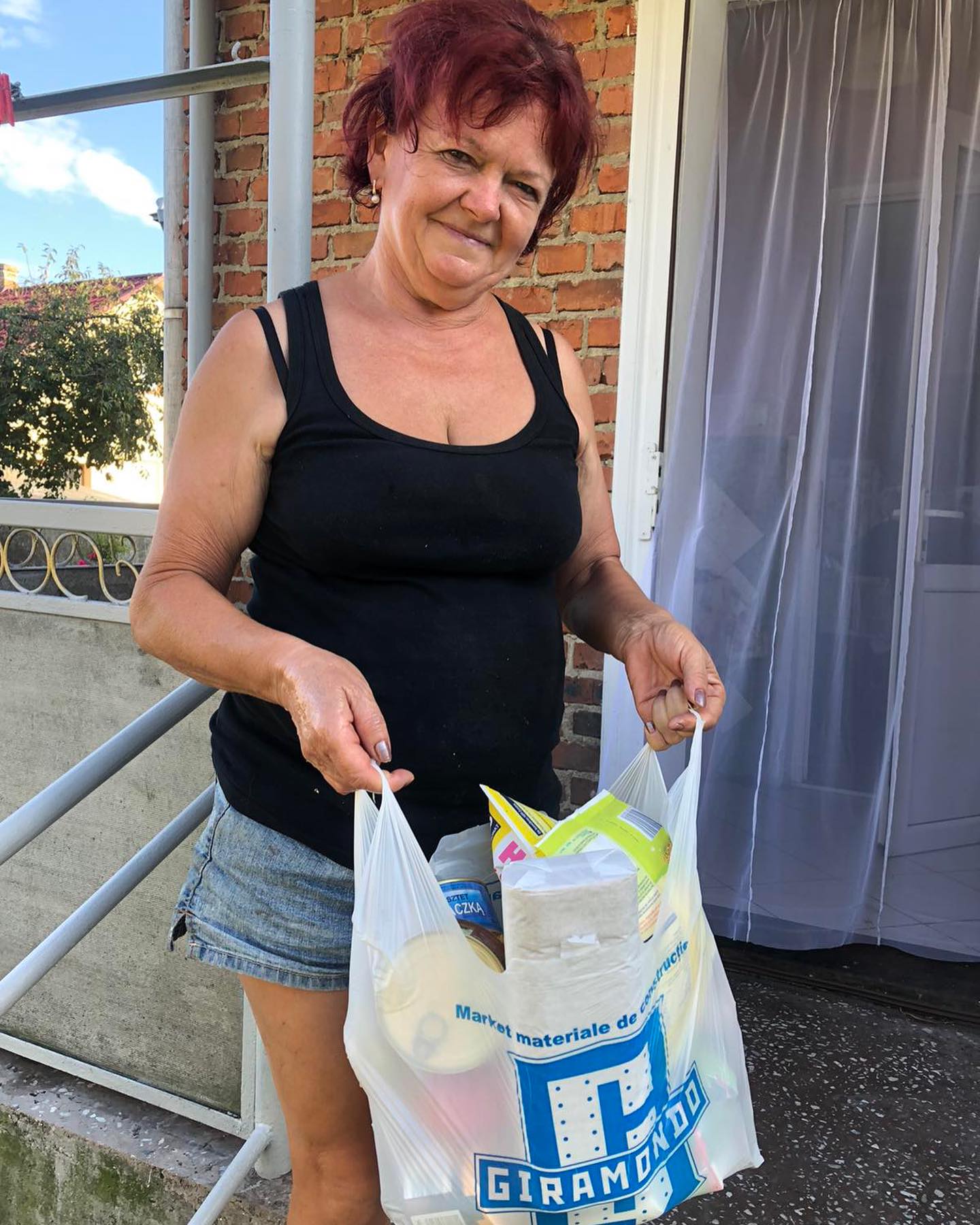 A woman holding a plastic bag with food in it.