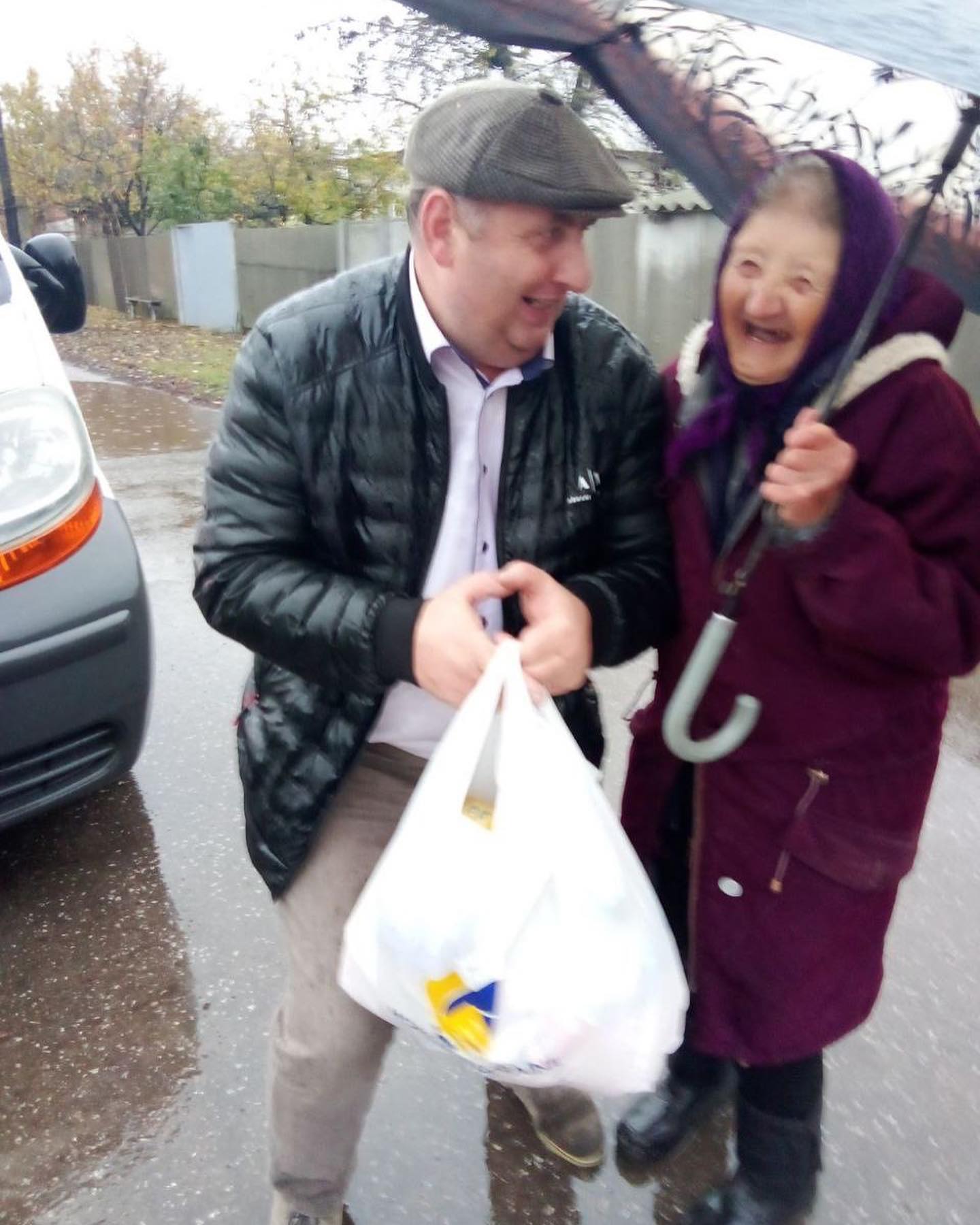 A man holding an umbrella and a woman holding a bag.