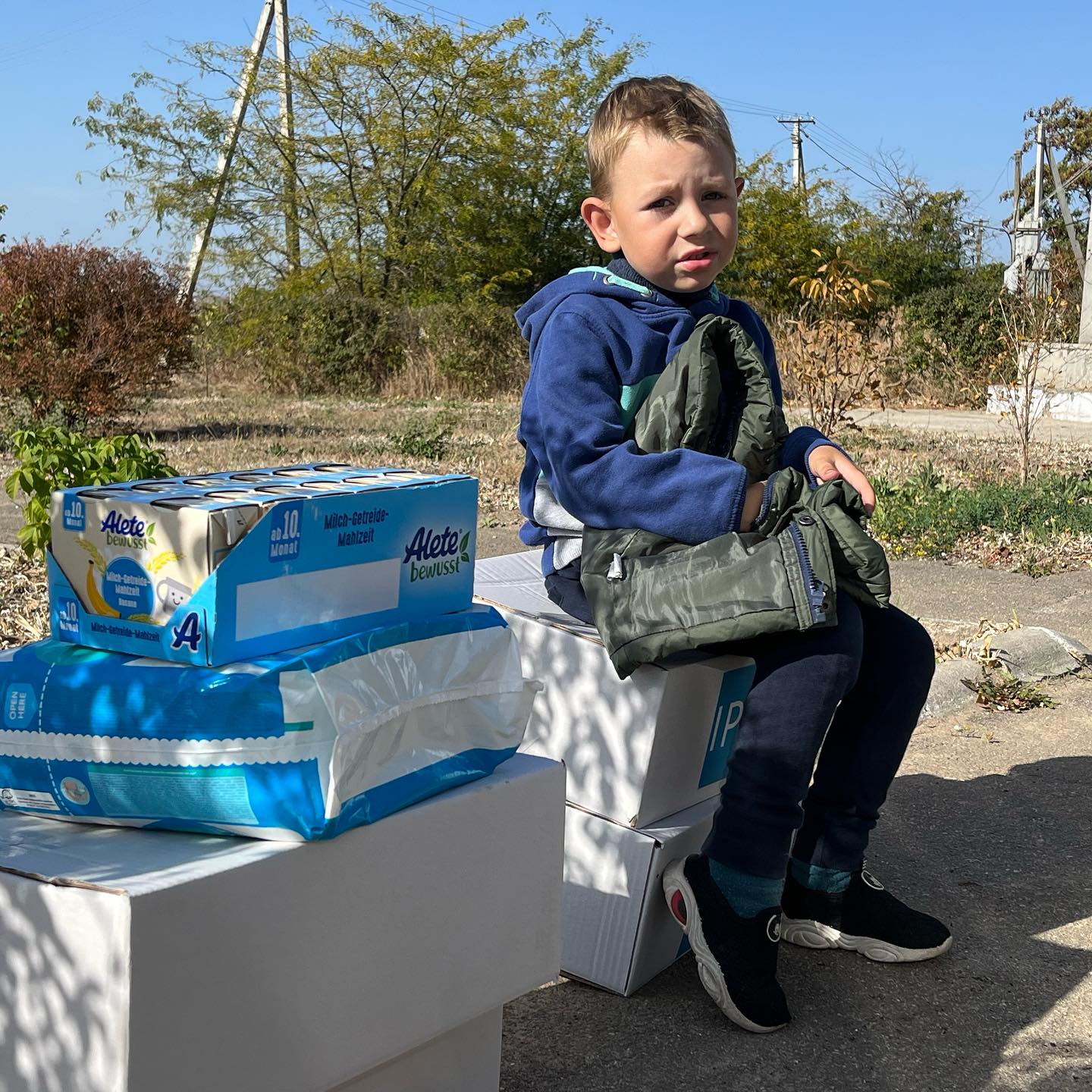 A young boy sits on top of boxes of toilet paper.
