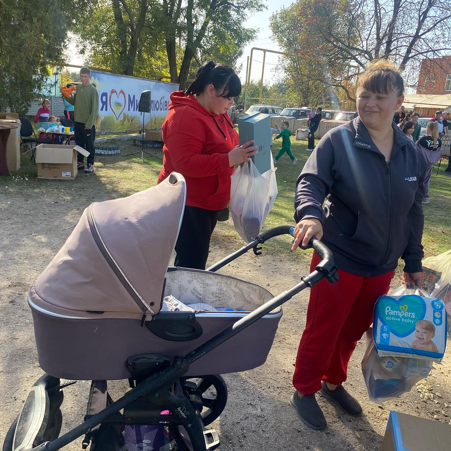 Two women standing next to a stroller with diapers in it.