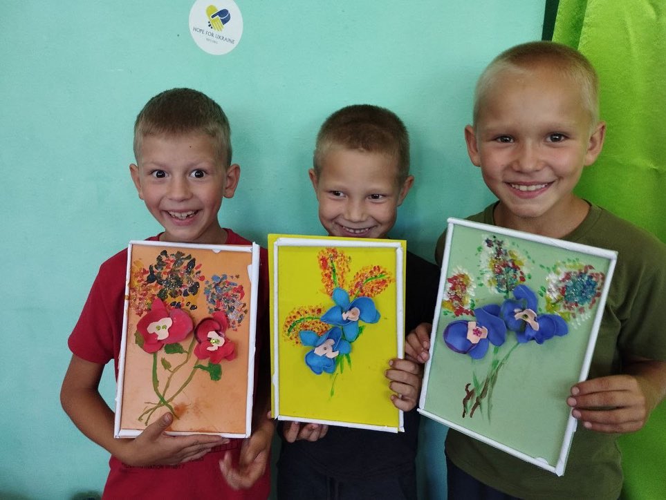 A group of young boys are holding up pictures of flowers.