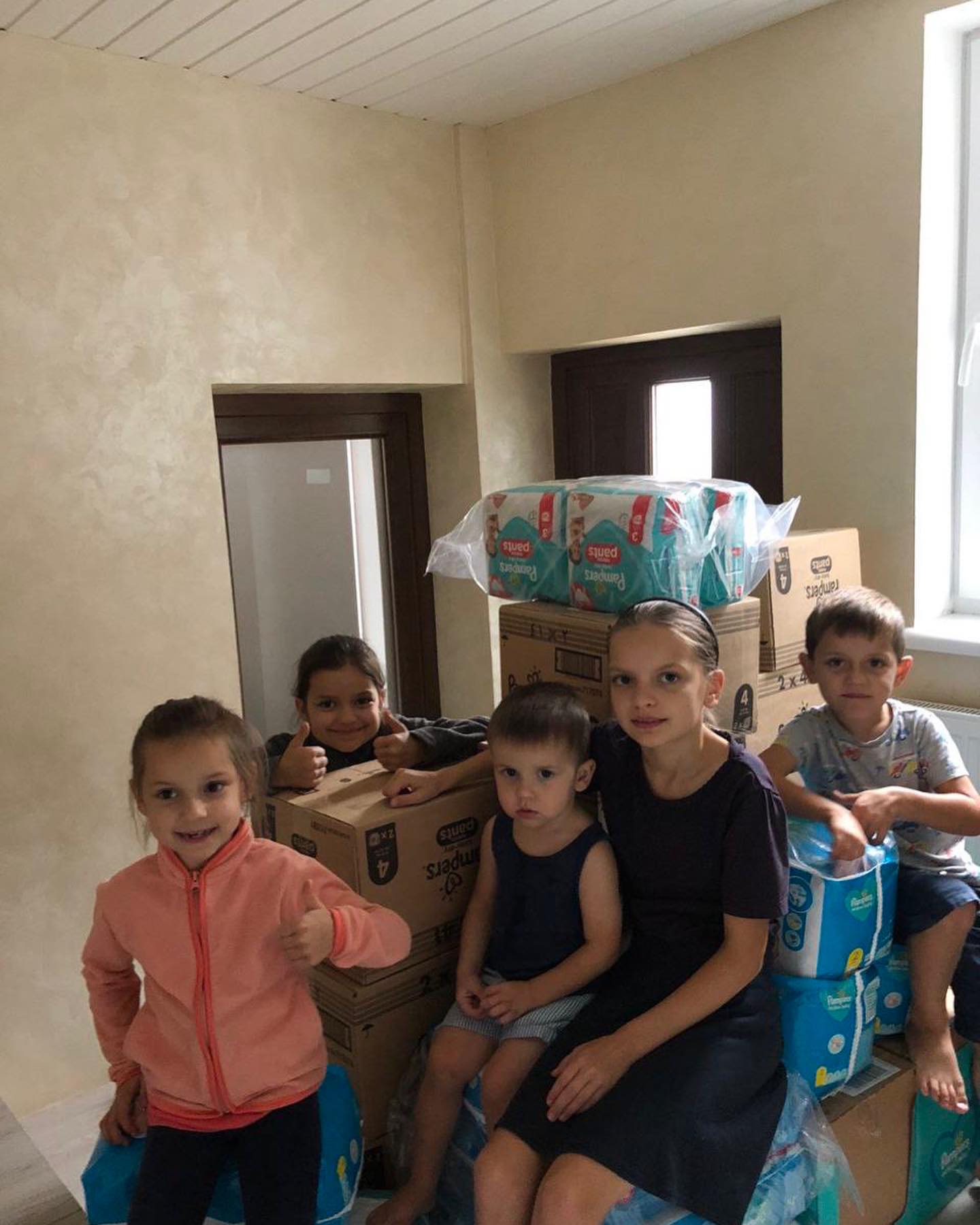 A group of children posing with boxes of diapers.