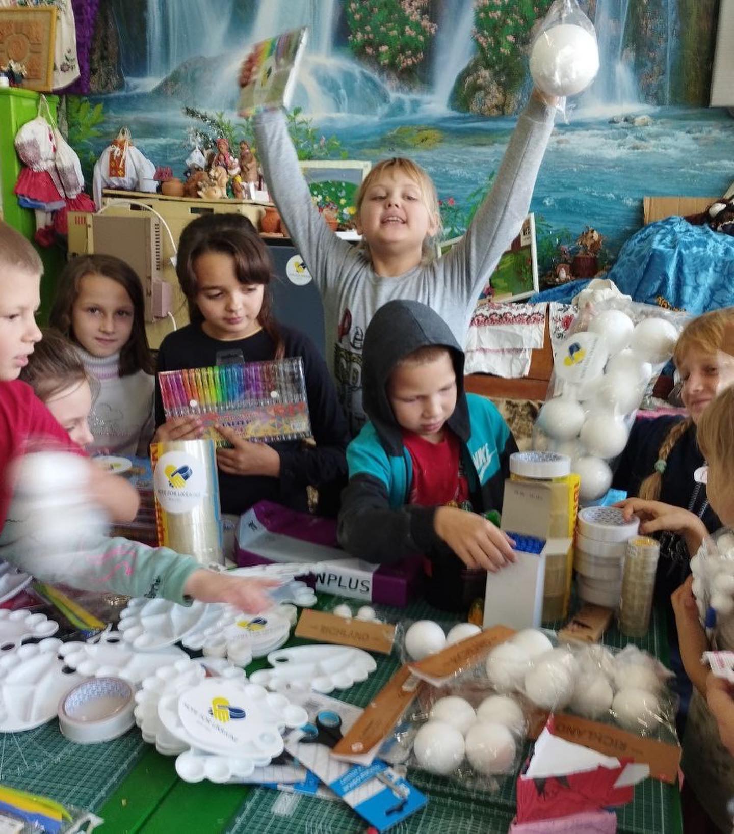 A group of children are sitting around a table making crafts.