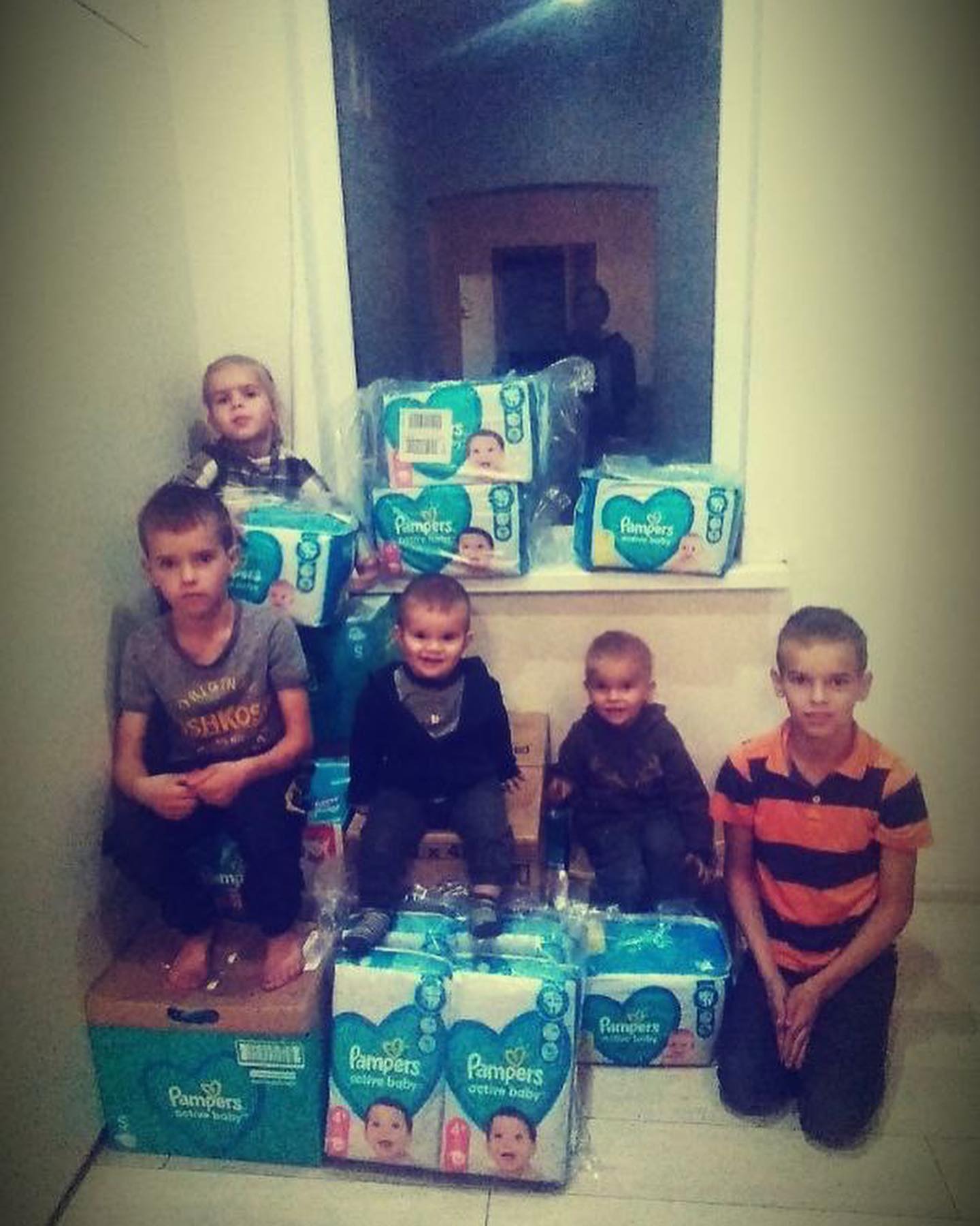 A group of children posing in front of boxes of diapers.