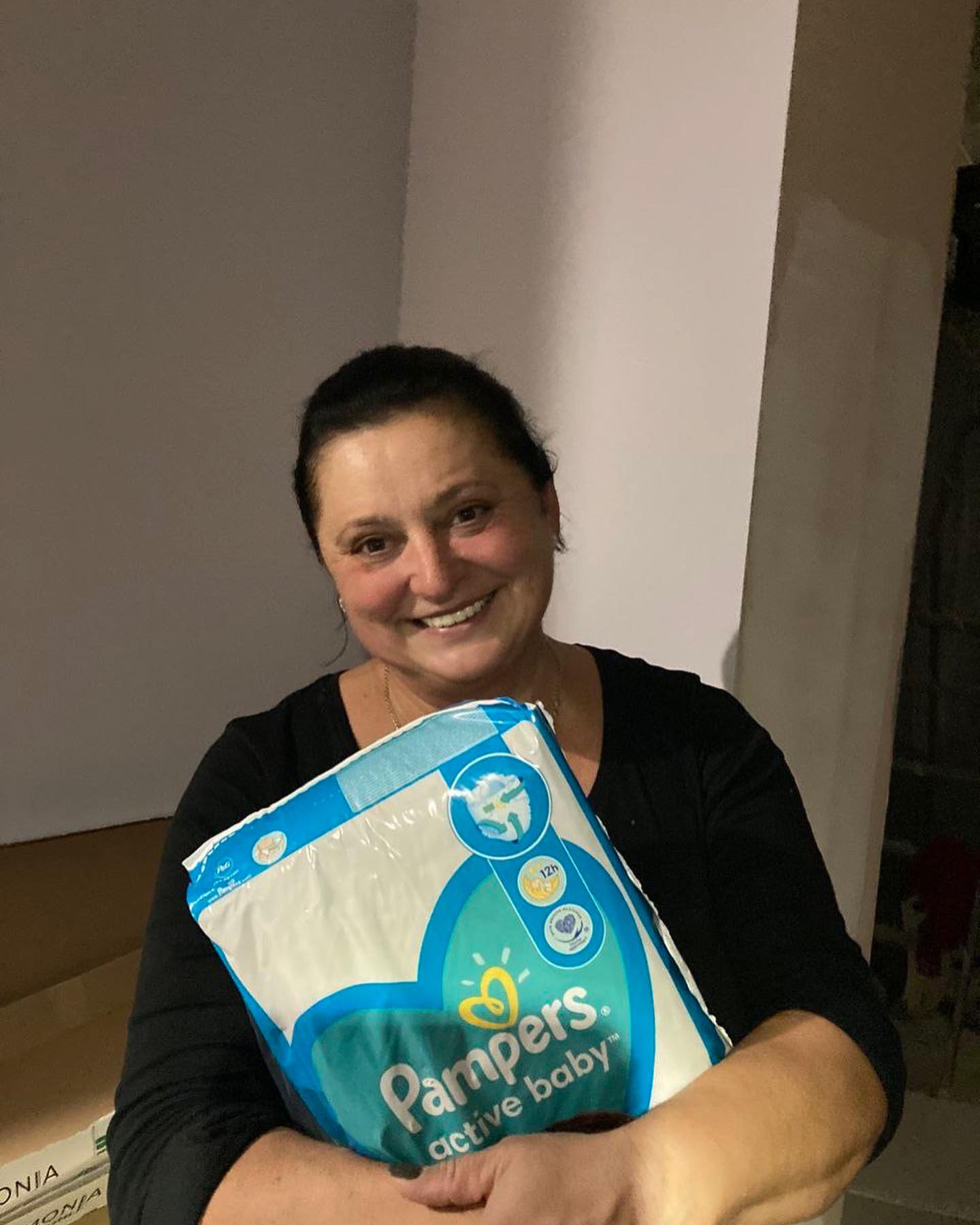 A woman holding a package of pampers diapers.