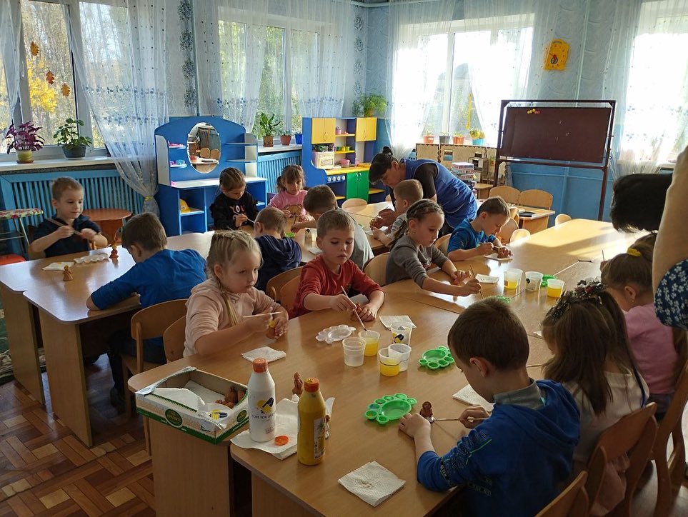 A group of children are sitting at a table in a classroom.