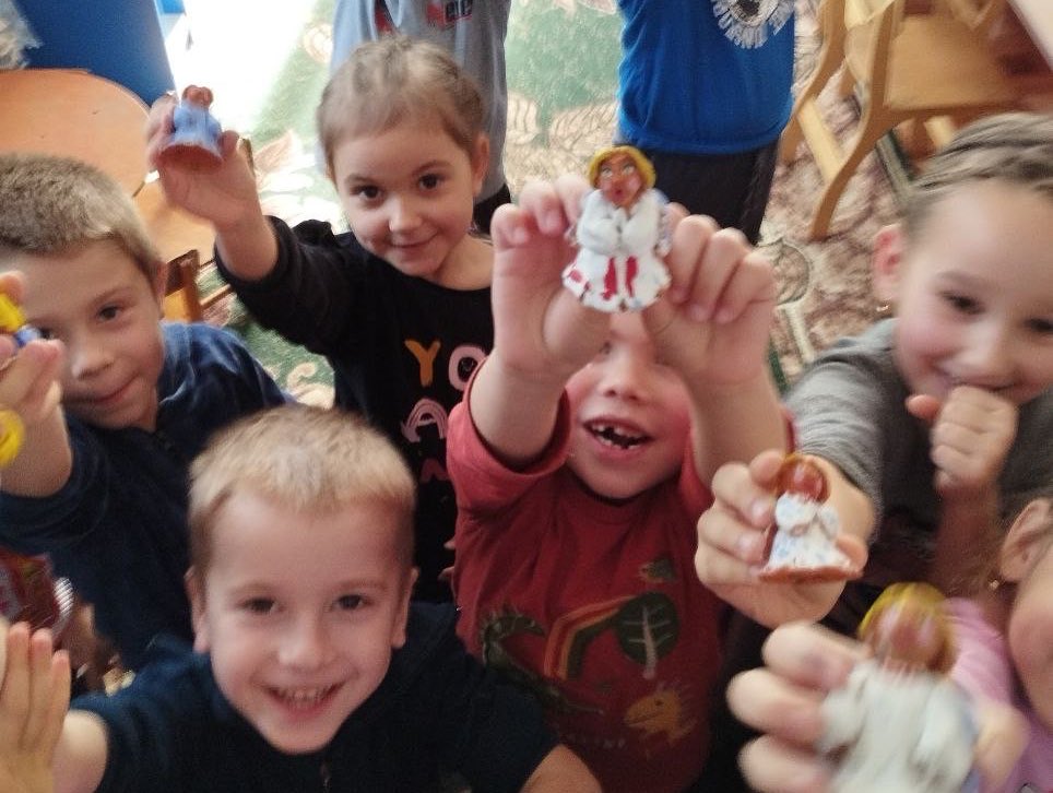 A group of children holding up figurines of jesus.