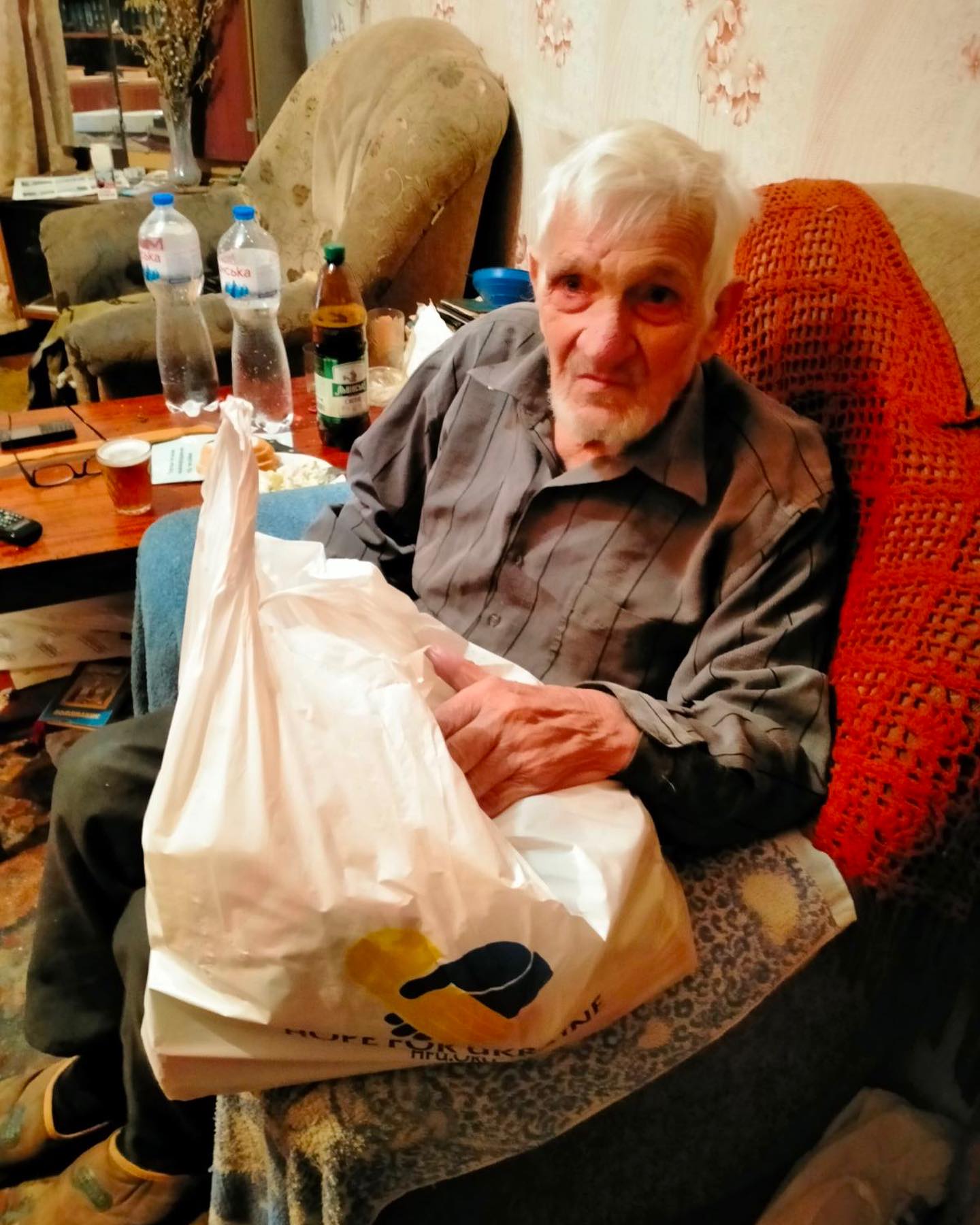 A man sitting on a couch holding a shopping bag.