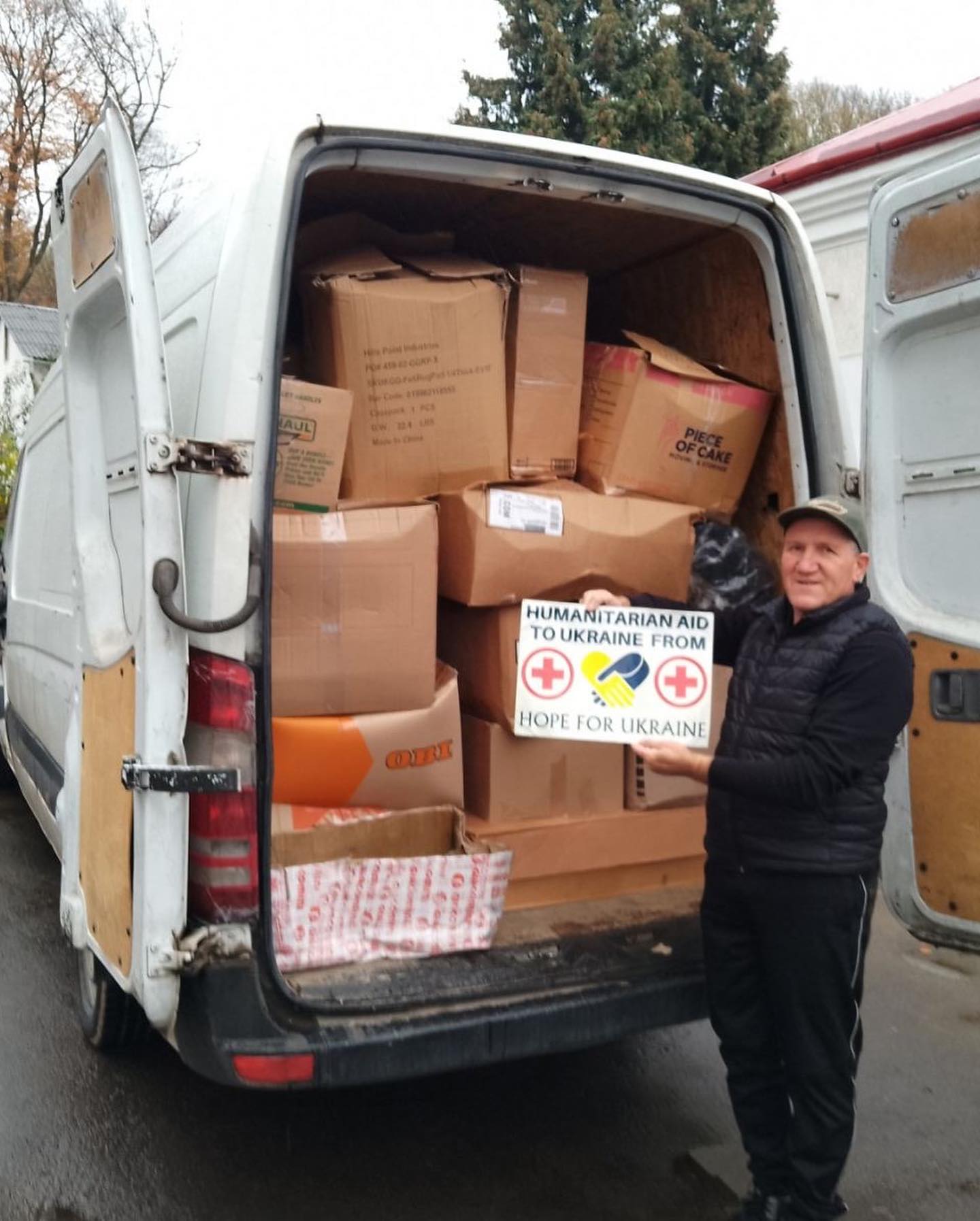A man standing next to a van full of boxes.
