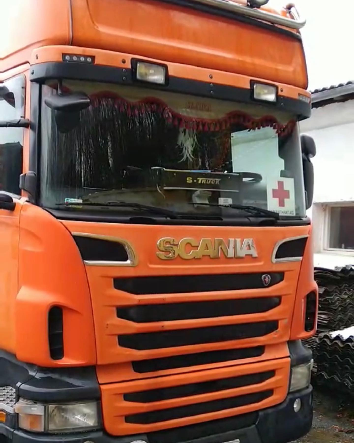 An orange truck is parked in front of a building.