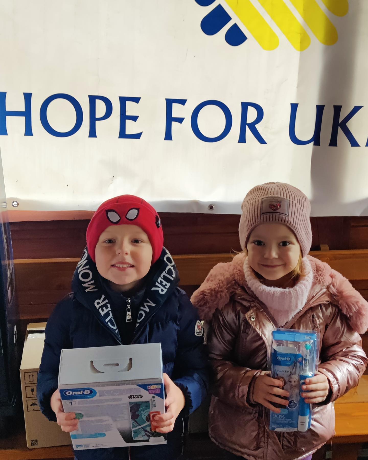 Two children standing next to a sign that says hope for ukraine.