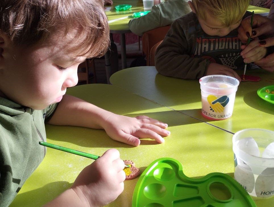 A group of children are sitting at a table and making crafts.