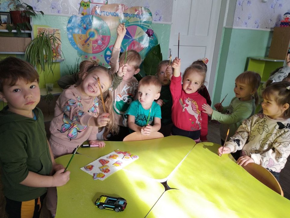 A group of children standing around a table.