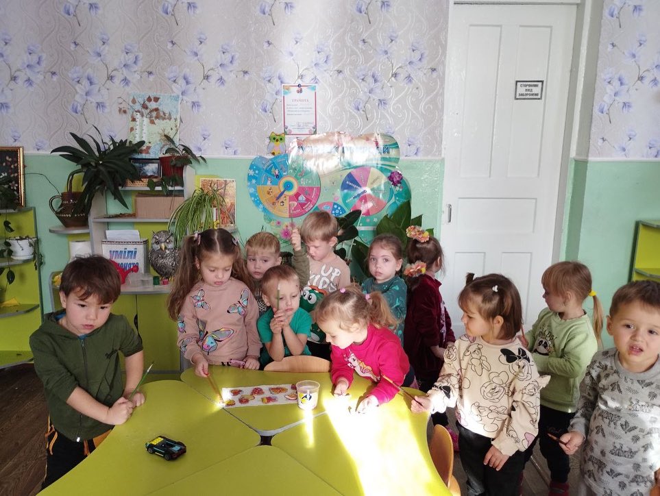 A group of children standing around a table in a classroom.