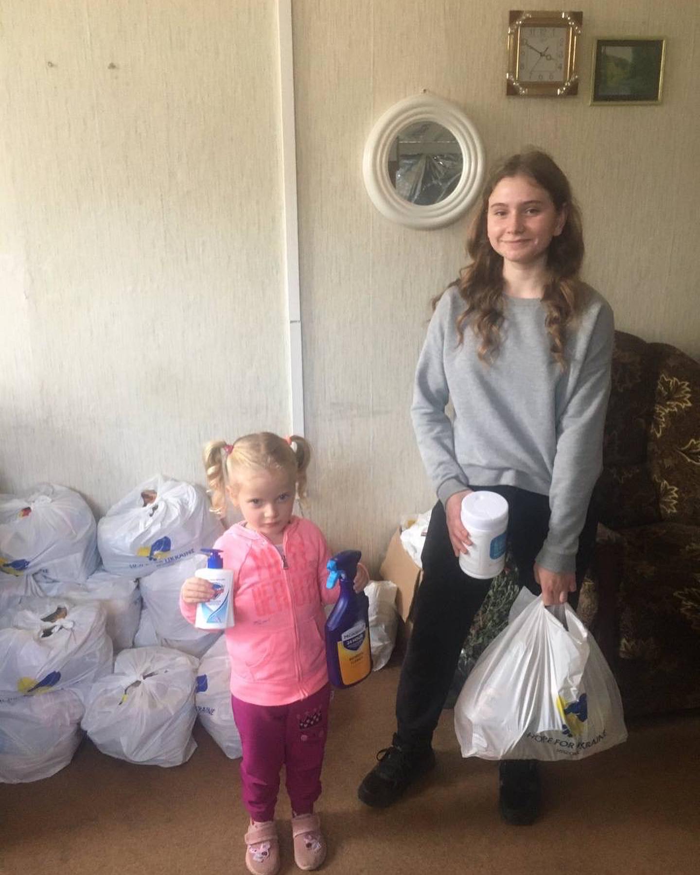 Two young girls standing in front of a room full of bags.