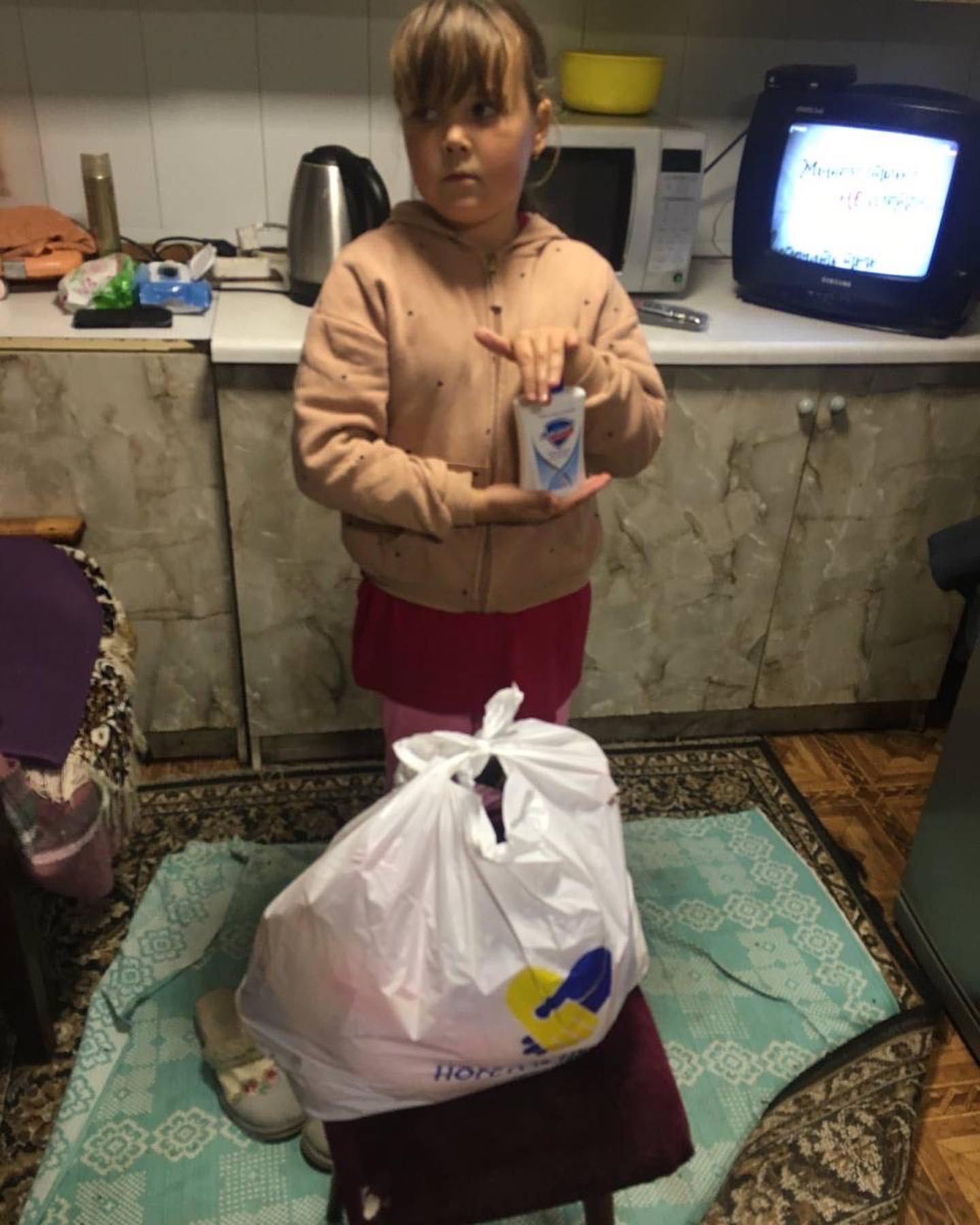 A girl standing in a kitchen holding a bag of food.